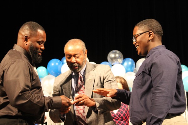 Principal Brewer offers ring to student at the Ring Ceremony.